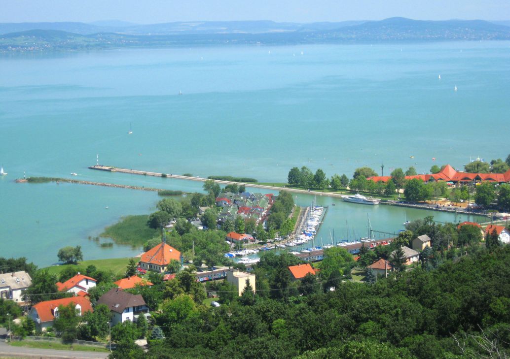 Panoramic view of Lake Balaton in Hungary with calm turquoise water, sailing boats and green hills in the background, showcasing the country’s popular summer lakeside holiday destination.